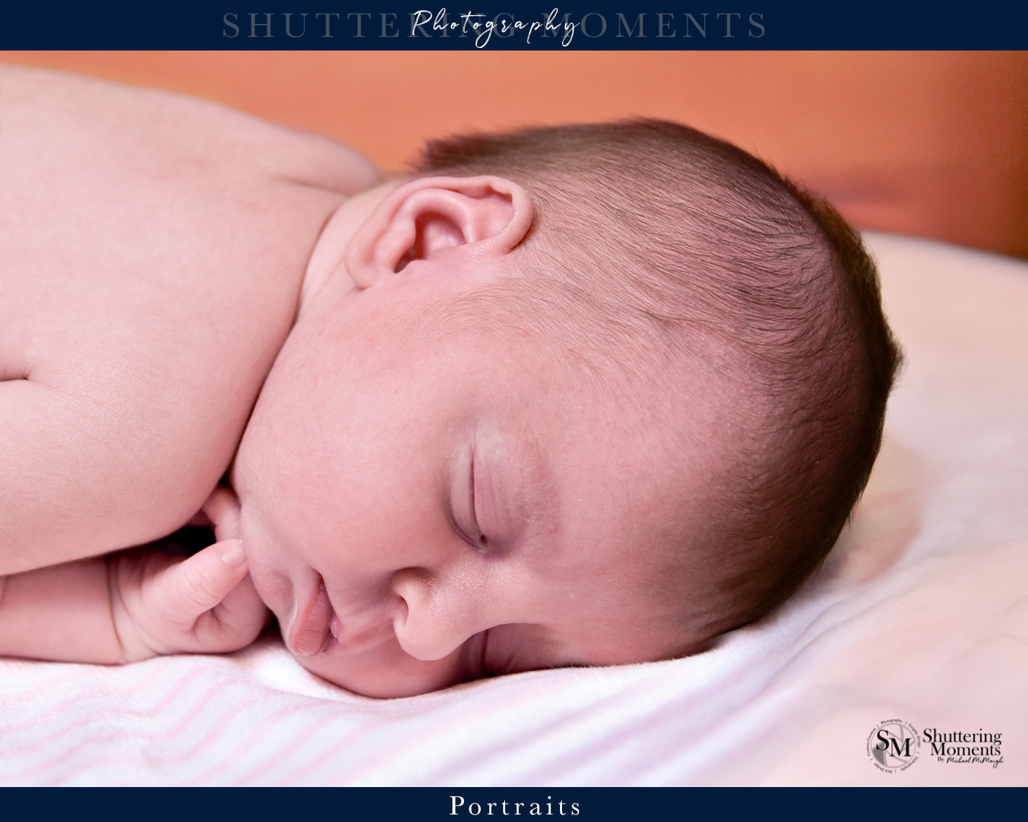 Newborn baby sleeping on a white blanket with an orange background in a peaceful pose.