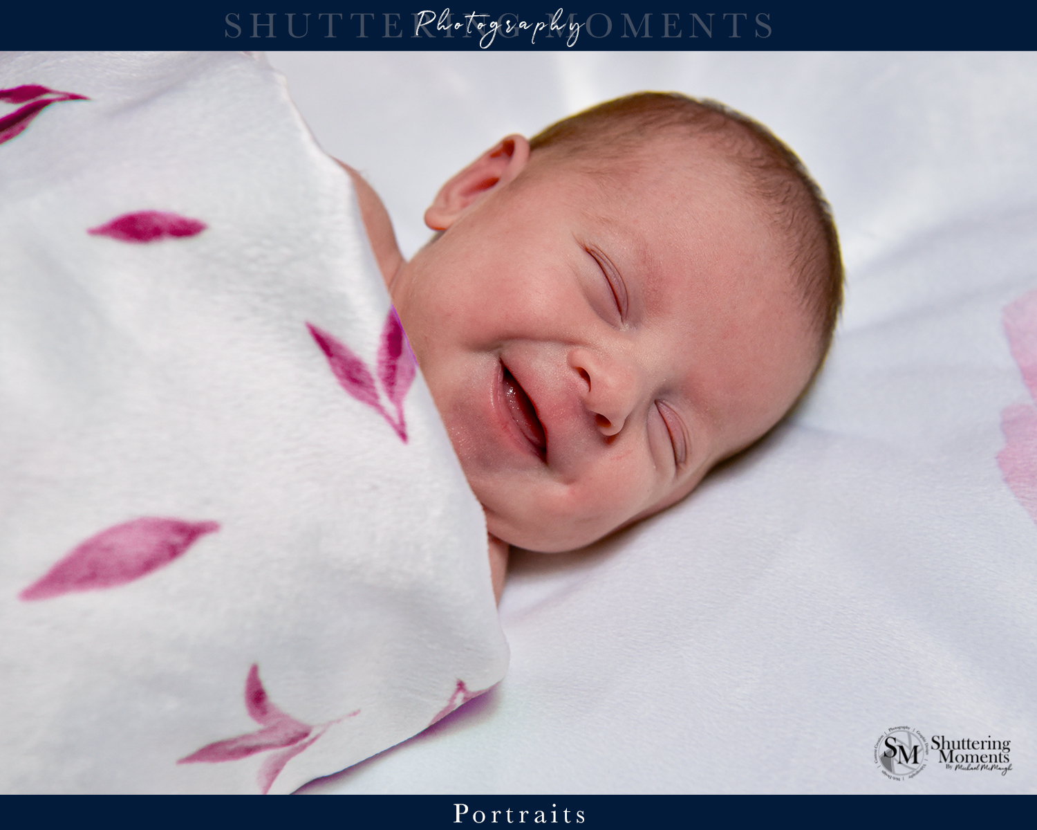 Newborn baby laughing and smiling with eyes closed, wrapped in a cozy blanket.