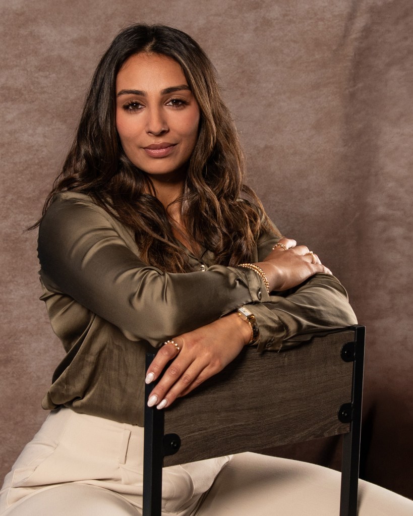 RE/MAX real estate agent Ana Sanchez seated behind a backwards chair wearing an olive green silk shirt during a branding photography session.